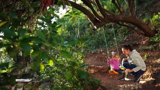 妈妈用绑在公园里一棵树上的绳子摆动着一个小女孩 高质量的4K镜头 — 图库视频影像