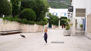 Little girl in sunglasses runs in the yard of the house. High quality 4k footage