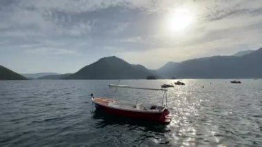 Small boat is rocking on the waves against the backdrop of mountains. High quality 4k footage