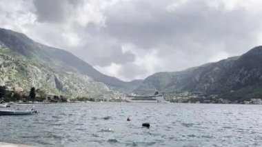 Beyaz yolcu gemisi, dağların arka planında kıyıya yakın duruyor. Yüksek kalite 4k görüntü