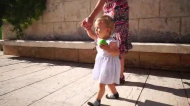 Annem küçük bir kızı çitten eve kadar fayanslar boyunca götürür. Yüksek kaliteli FullHD görüntüler