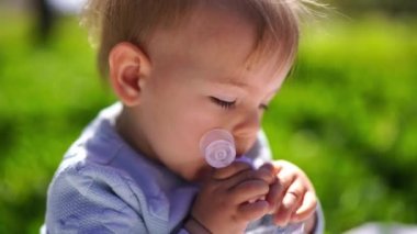 Little girl with a daisy behind her ear trying to open a bottle of water. High quality 4k footage
