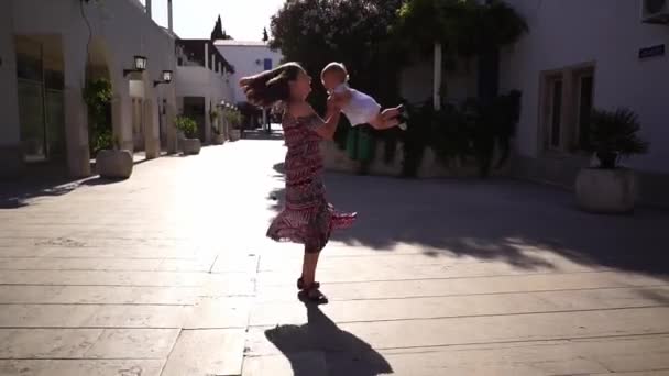 ママは庭の家の間の庭で小さな女の子を旋回している スローモーション 高品質のフルHd映像 — ストック動画