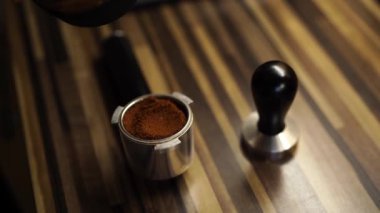 Barista spoons ground coffee into the portafilter and presses it with tamper. High quality 4k footage