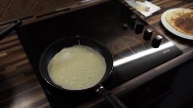 Pancake is baked in a frying pan on the stove covered with bubbles. High quality 4k footage