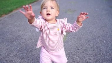 Small baby walks on the asphalt raising his hands up. High quality FullHD footage