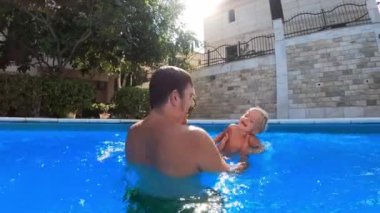 Dad is spinning with a little laughing girl in his arms in the pool. High quality 4k footage