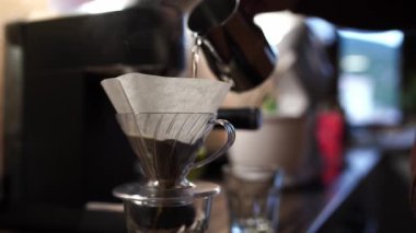 Barista pouring boiling water into a pour over filter coffee maker. High quality 4k footage
