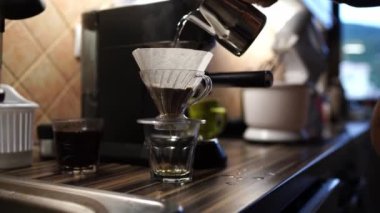 Man pours boiling water from a jug into a filter of a glass pour over coffee maker. High quality 4k footage