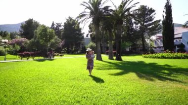 Mom with a little girl in her arms walks on a sunny lawn. High quality FullHD footage