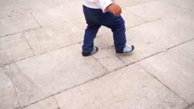 Little baby learns to walk on tiles in the yard. Cropped. High quality FullHD footage