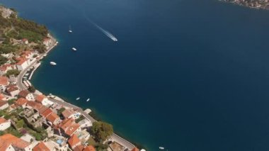Motor yacht sails past the coast of Perast on the blue sea. Drone. High quality 4k footage