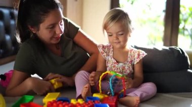 Mom shows the little girl Lego blocks lying on the bed. High quality 4k footage