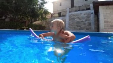 Little girl swims with mom on an inflatable stick. High quality 4k footage