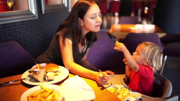 소녀는 식탁에 식당의 의자에 감자튀김으로 어머니를 고품질 — 비디오