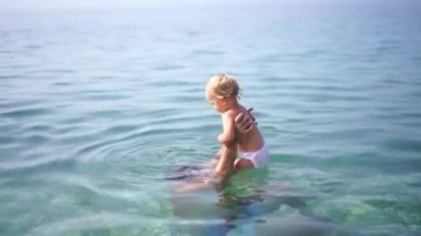 Dad plays with a little girl in his arms in the sea. High quality 4k footage