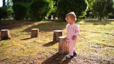 Little girl runs among the stumps on a green lawn. High quality FullHD footage