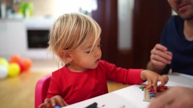 Küçük kız ve baba masada oturup plastik adamlar yontuyorlar. Yüksek kalite 4k görüntü