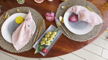 Green uramaki set on a rectangular dish stands on a laid festive table. High quality 4k footage