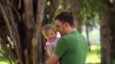 Dad spinning with a little girl in his arms in the park. High quality 4k footage
