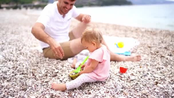 Dad Pours Small Pebbles Bowl Little Girl Sitting Pebble Beach — Stockvideo