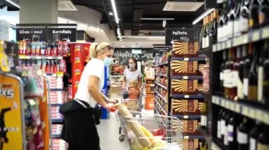 Mom with a little girl in a shopping cart walks through the supermarket. High quality 4k footage