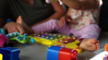 Little girl sits next to her mother and plays with a soft dragon. High quality 4k footage