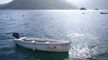 Small fishing boat sways on the waves moored with a rope to the shore. High quality FullHD footage