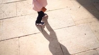 Small child takes the first steps on the tiles in the yard. Cropped. High quality FullHD footage