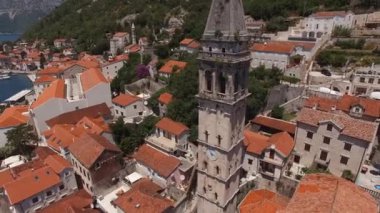 Ancient church belfry with a clock on the facade in Perast. Drone. High quality 4k footage