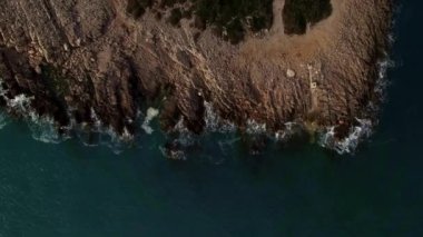 Green waves crash against the rocky coast. Aerial view. High quality 4k footage