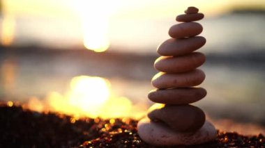 Pyramid of stones on a pebble beach in the reflections of the setting sun. High quality 4k footage