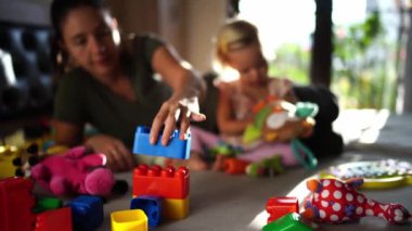 Little girl plays with a soft owl while her mom builds a Lego house. High quality 4k footage