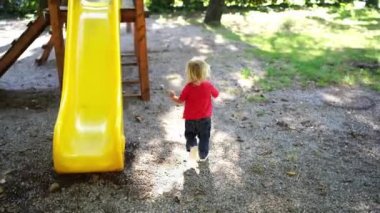 Little girl runs to the stairs to climb the slide in the playground. High quality 4k footage