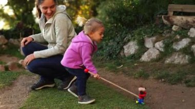 Little girl carries a toy dog on wheels along a path in the garden. High quality 4k footage