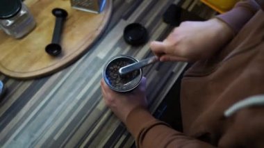 Man grinds coffee beans in a manual coffee grinder on a table. High quality 4k footage