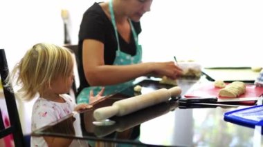 Mom teaches her little daughter how to make pies with filling at the table in the kitchen. High quality 4k footage