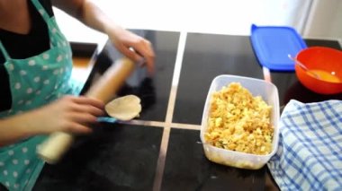 Woman rolls out the dough for a bun and pours the filling with a spoon. High quality 4k footage