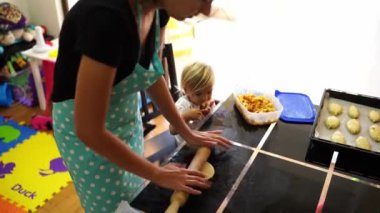 Little girl tries the filling next to her mother rolling the dough into buns. High quality 4k footage