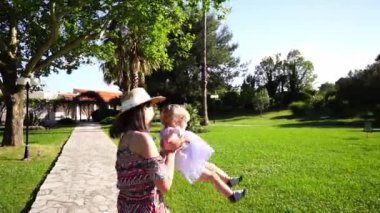 Annem parkta küçük bir kızın kollarında daireler çiziyor. Yüksek kaliteli FullHD görüntüler