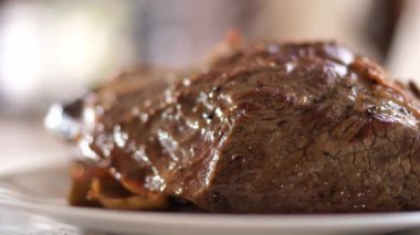 Juicy piece of roast beef is steaming on a plate on the table. High quality 4k footage