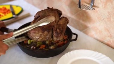 Housewife transfers roast beef from a frying pan to a plate with tongs. High quality 4k footage