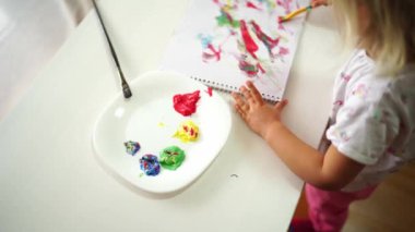 Little girl draws with a brush with paints in the album. High quality 4k footage