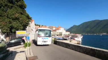 Tour bus travels along the narrow street of Perast above the sea. Montenegro. High quality 4k footage