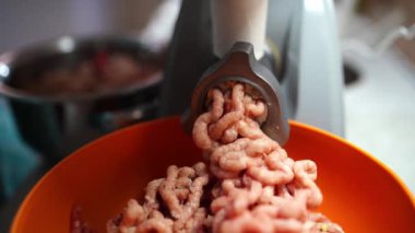 Long straws of minced meat come out of the grinder into a bowl. High quality 4k footage