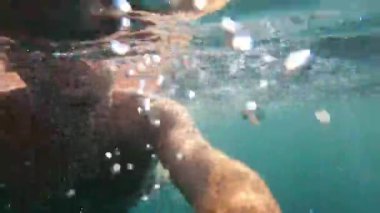 Young man swims in the sea. View from underwater. High quality 4k footage