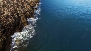Waves crash against the rocky shore, indented by the sea. Drone. High quality 4k footage