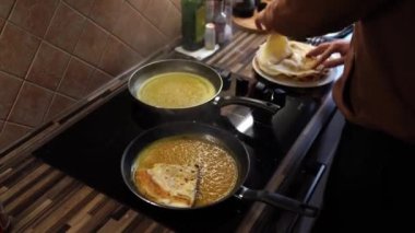 Chef puts pancakes rolled up in envelopes in a boiling sweet sauce in a pan. High quality 4k footage