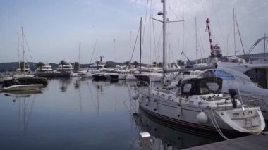 Rıhtımın yakınındaki yatlarla dağların arkasına doğru yelken açıyoruz. Porto, Karadağ. Yüksek kaliteli FullHD görüntüler