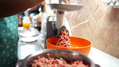 Housewife twists meat in an electric meat grinder pushing it with a pusher in a tray. High quality 4k footage